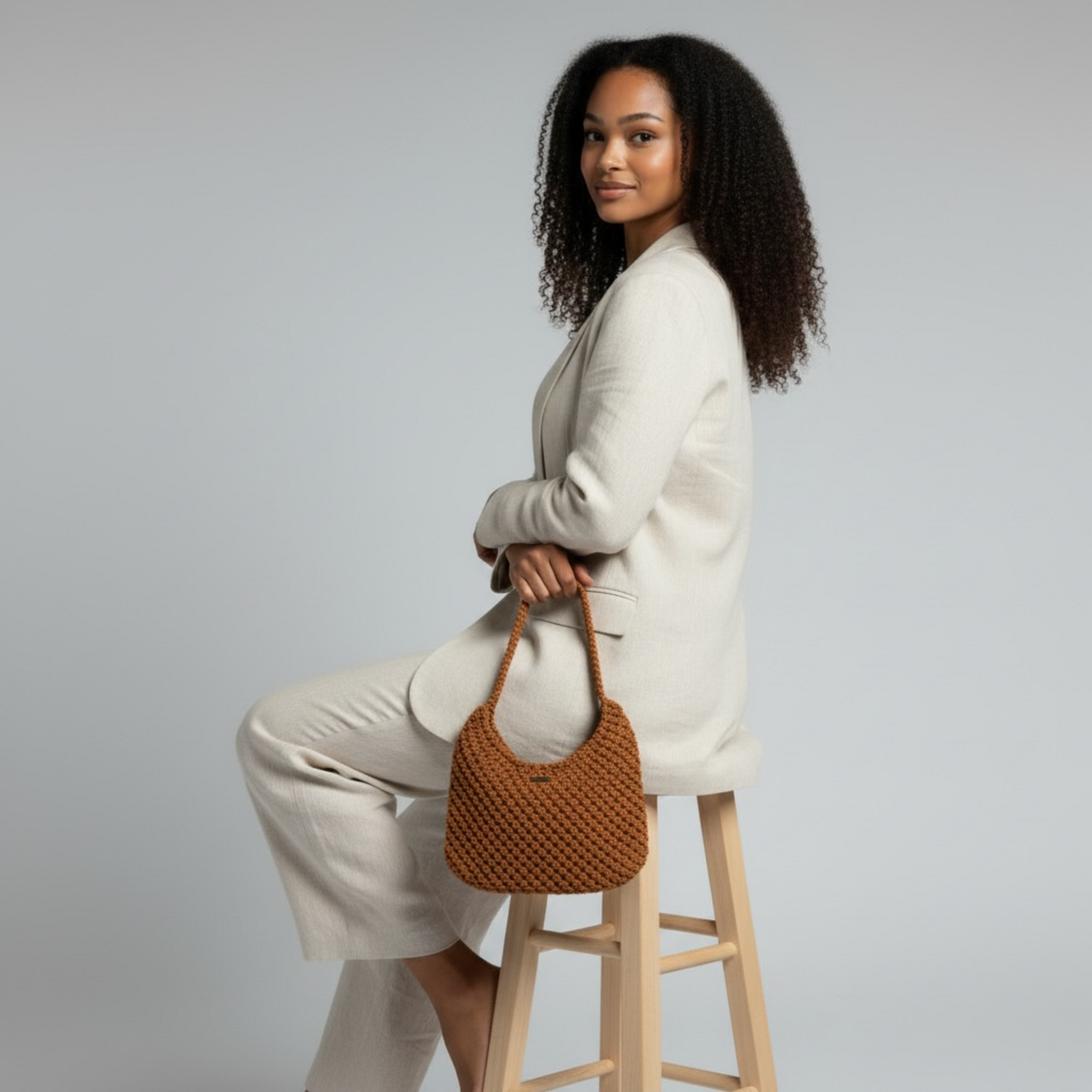Side view of burnt orange woven shoulder bag carried by model in neutral outfit, modern luxury styling
