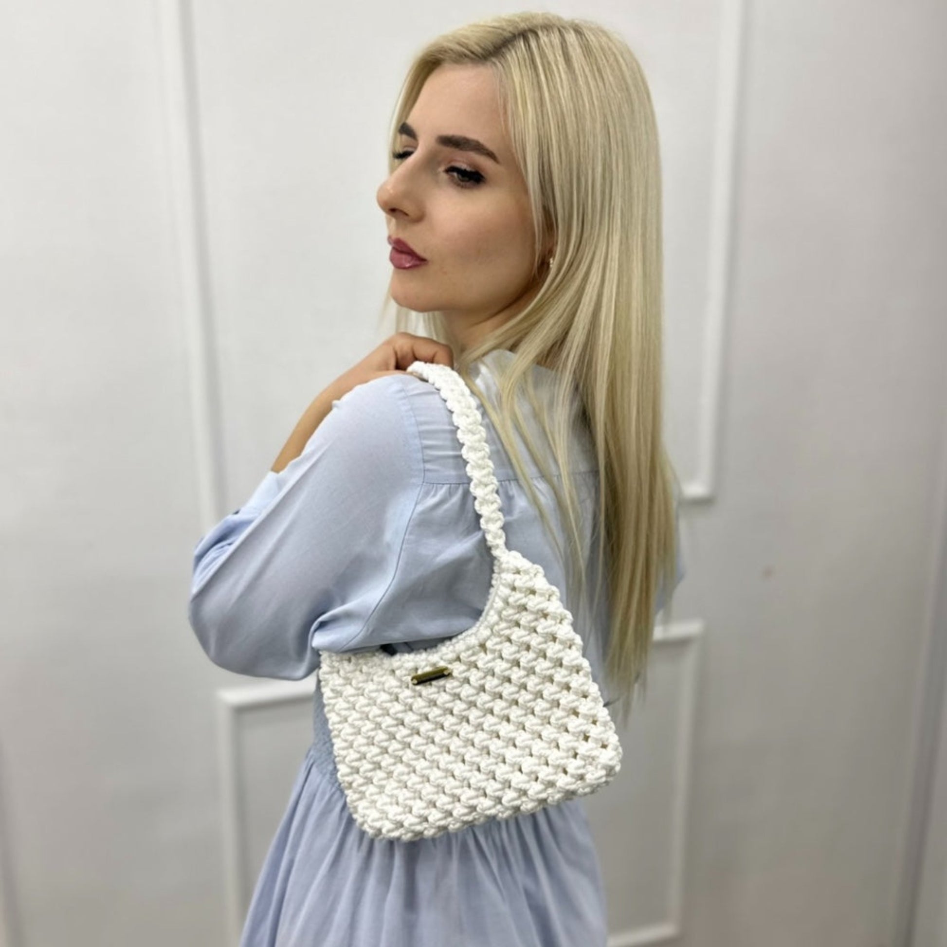 Woman wearing ivory white macrame shoulder bag with light blue outfit, minimalist style