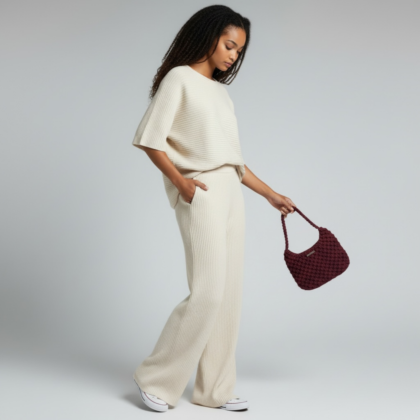 Model holding a merlot plum handmade macrame shoulder bag styled with neutral outfit