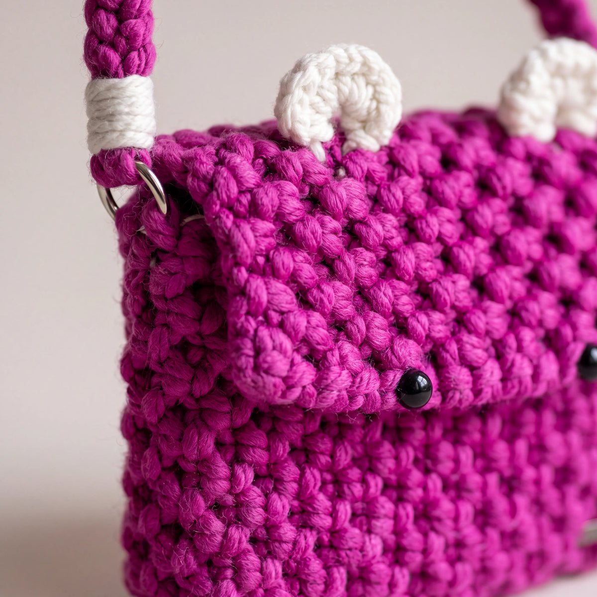 Side view of the Berry Bear macrame crossbody bag showing its structured depth, strap attachment and silver-tone ring.