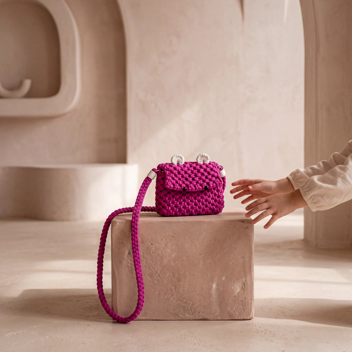 Fuchsia Berry Bear handmade macrame bag displayed on a neutral pedestal in a softly styled interior.