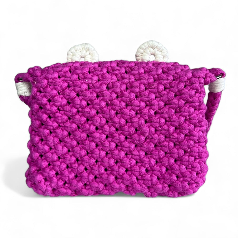 Back view of the handmade fuchsia macrame crossbody bag for kids, showing its dense cotton stitch texture.